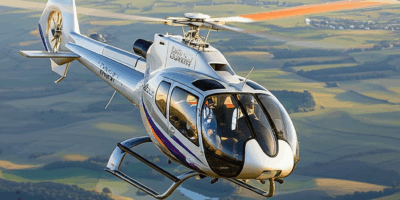 Bell 505 light turbine helicopter flying over scenic landscape